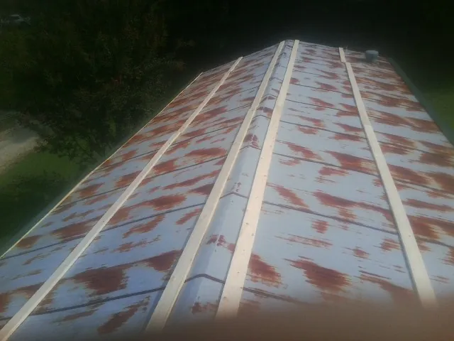 Rusted metal roof panels with new wood purlins before replacement — Storm Damage Roof Repair in Esmond by Roofing Brothers