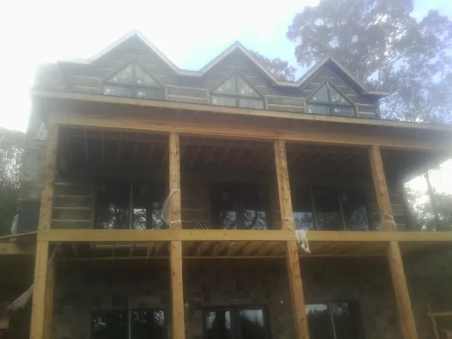 Dormers and porch framing on a large log home under construction — Roof Coating work by our crew in Esmond