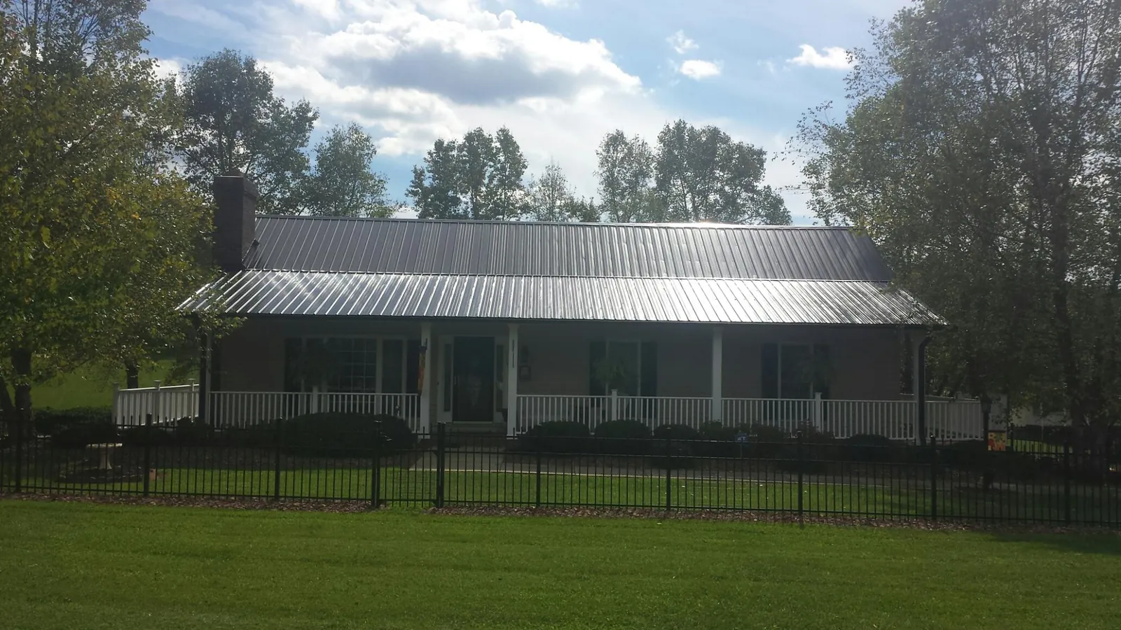 Gray metal roof on a brick ranch with a full width front porch — Gutter Guard Installation work by our crew in Esmond